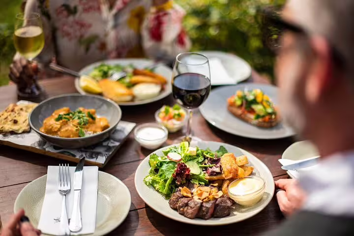 Gourmet dining experience with diverse dishes and wine on an outdoor table during a culinary exploration tour.