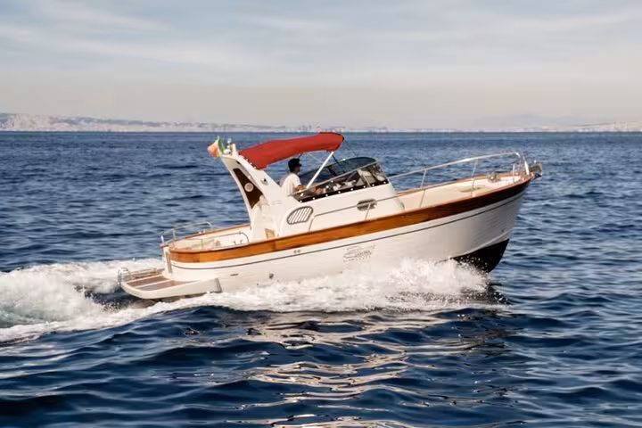 Typical Gozzo 750 boat gliding through blue waters on a private tour from Sorrento to Positano and Amalfi coast.