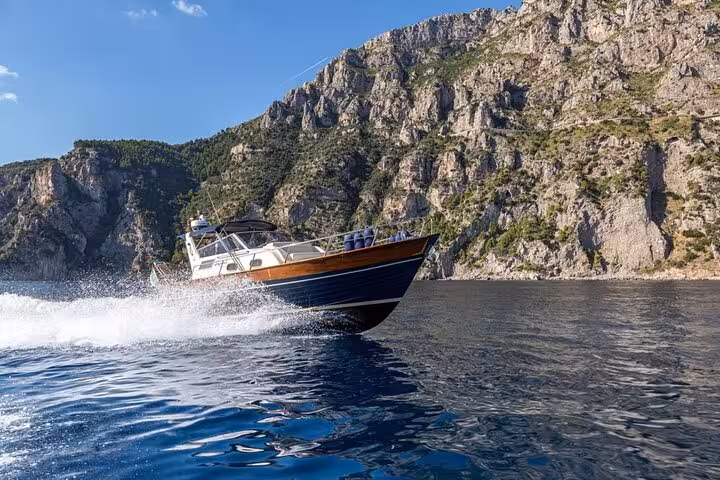 Gozzo Apreamare 10 cruising along Positano's dramatic cliffs on a sunny day tour from Sorrento.