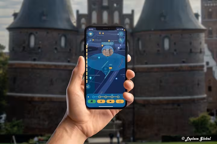 Hand holding GPS ghost tour app smartphone in front of Lubeck's iconic medieval Holstentor gate landmark