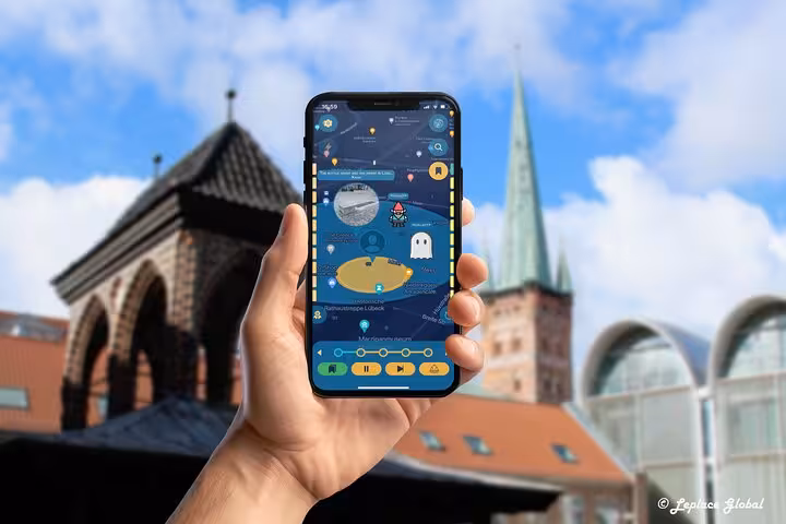 Hand holding a smartphone with GPS ghost hunting tour app in Lubeck with historic buildings in background
