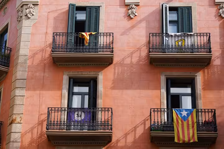 Colorful Gràcia balconies with Catalan flags on a pink facade, a stop on the vermouth tasting tour
