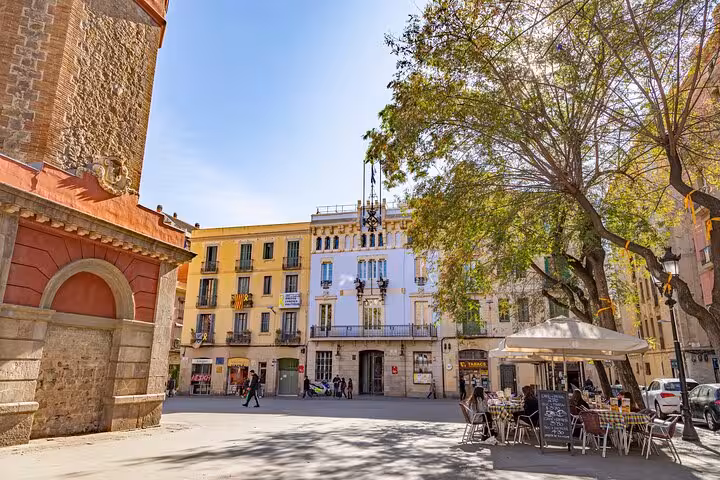 Sunny Gràcia square with terrace cafés and historic buildings, Barcelona, on a Catalan culture and cuisine tour