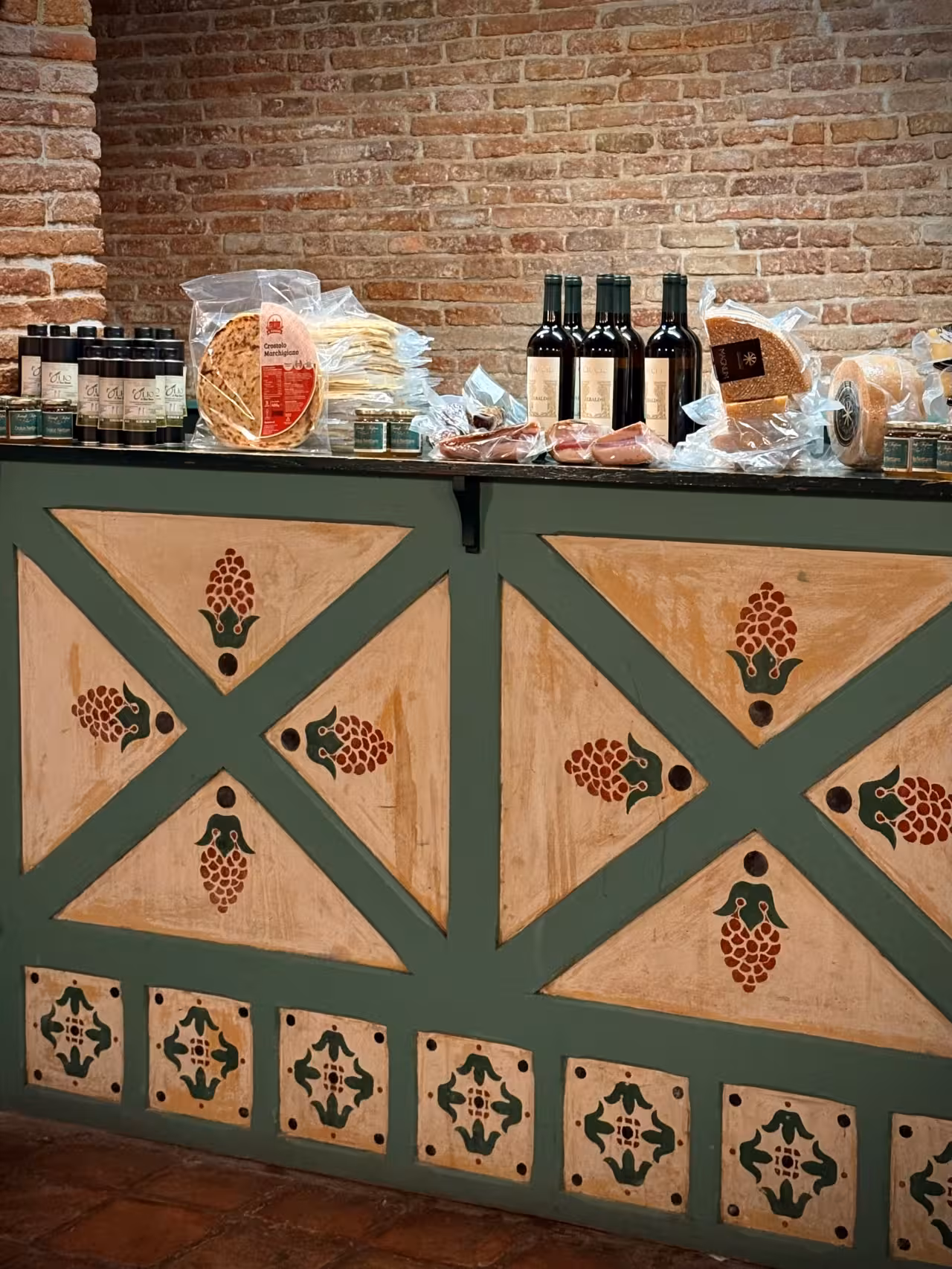 Gradara food tasting counter with local olive oil, cured meats, flatbread and Marche wine bottles in rustic cellar