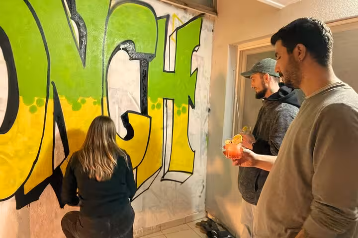 Guests sip cocktails while painting a bold graffiti mural with locals on the Sip and Spray street art workshop