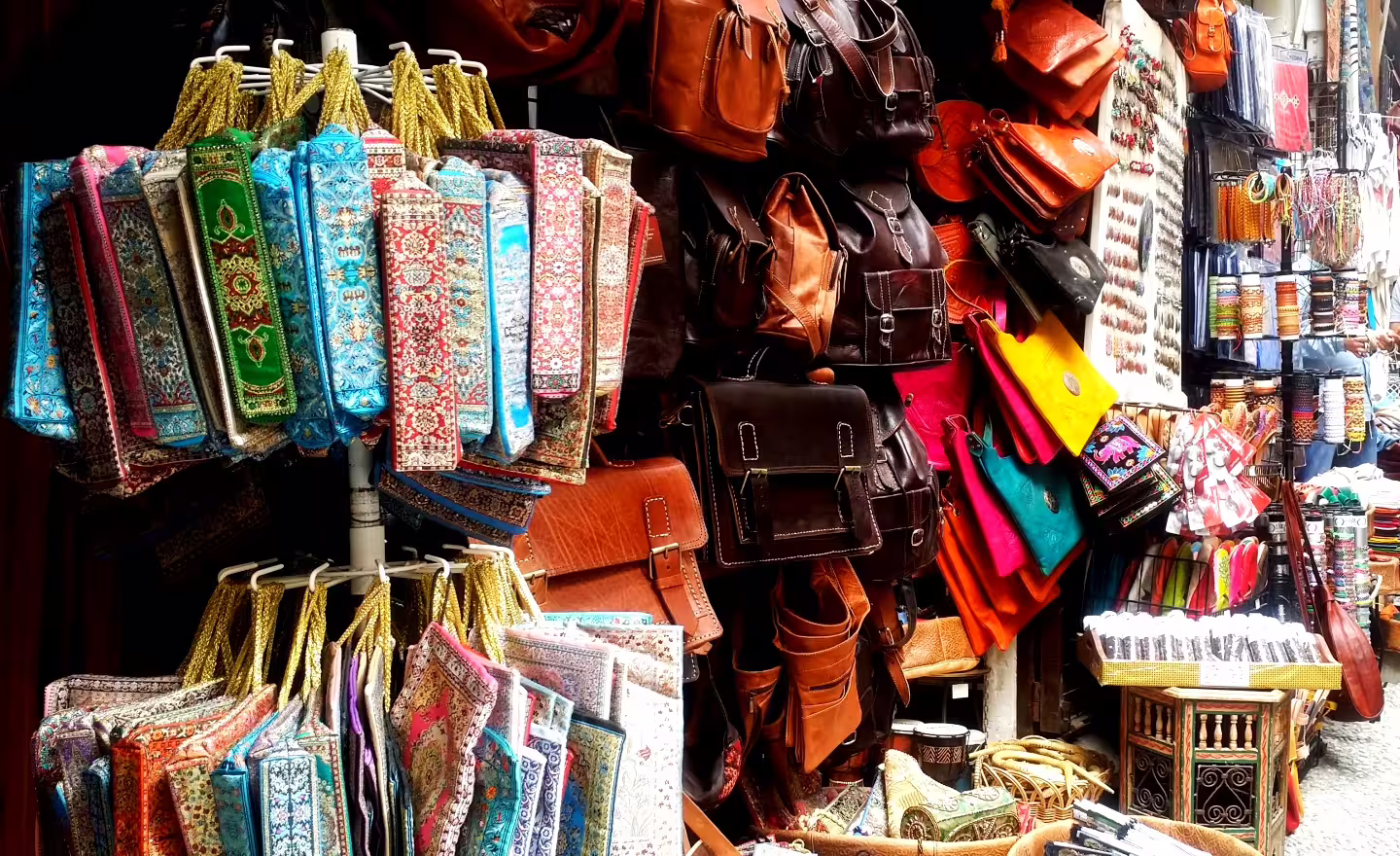 Colorful Granada souk stall with leather bags and patterned textiles, a stop on Costa del Sol to Alhambra tour