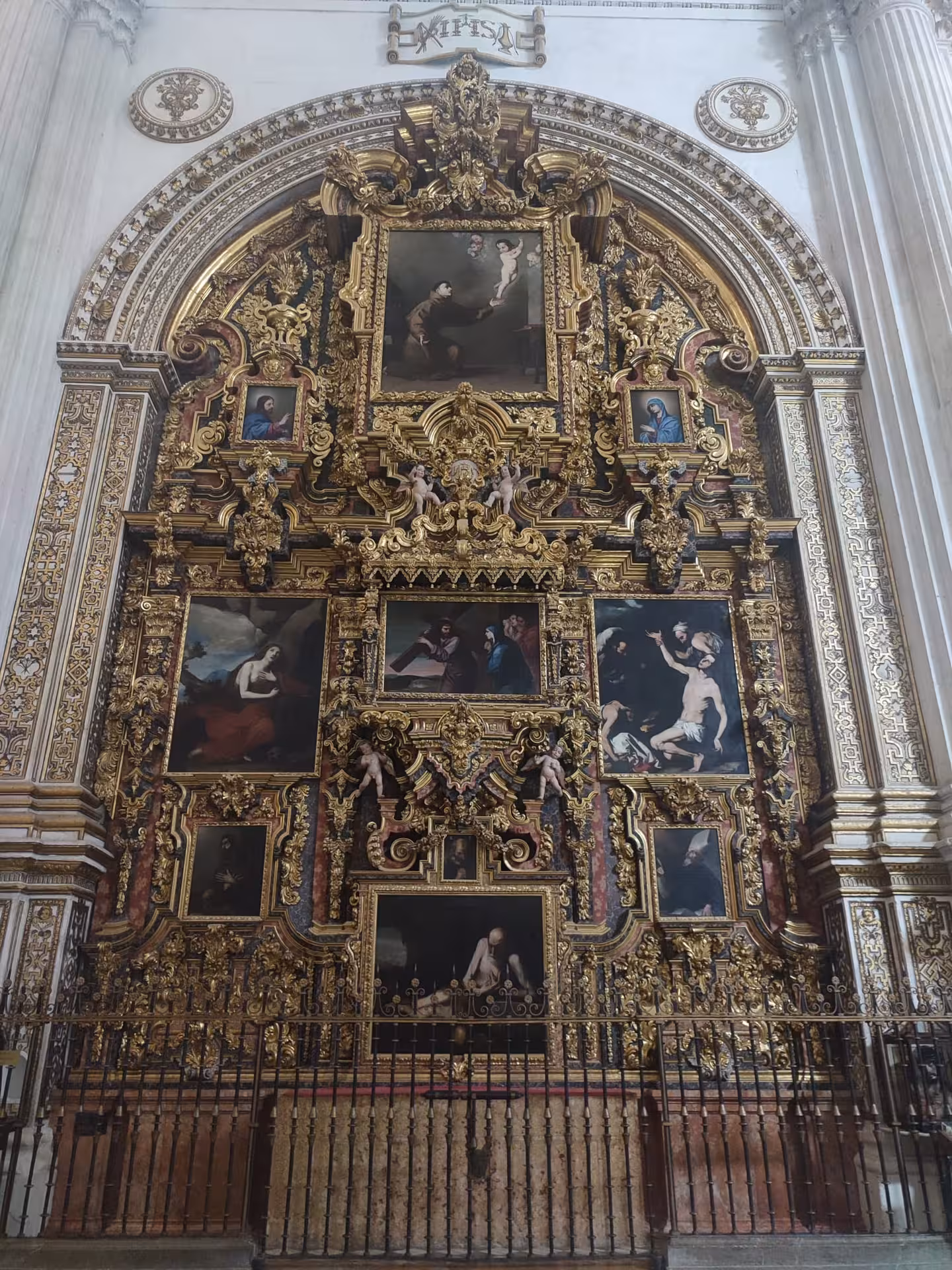 Elaborate altarpiece in the Royal Chapel of Granada, featuring detailed religious artwork and gilded frames.