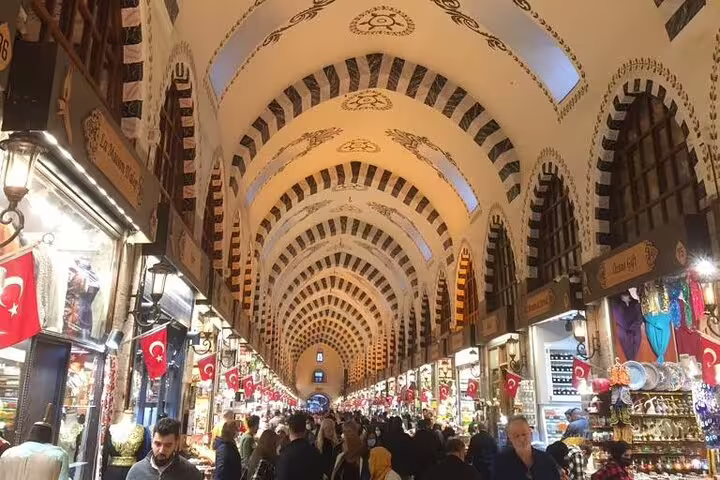 Grand Bazaar Istanbul arched corridor with Turkish flags and shops, included in Turkey 13-day private guided tour