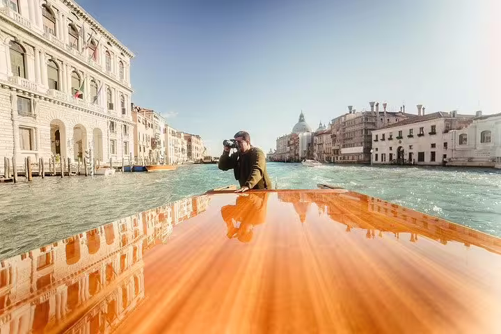 Photographer capturing the scenic Grand Canal view from a wooden boat during Murano and Burano private tour.