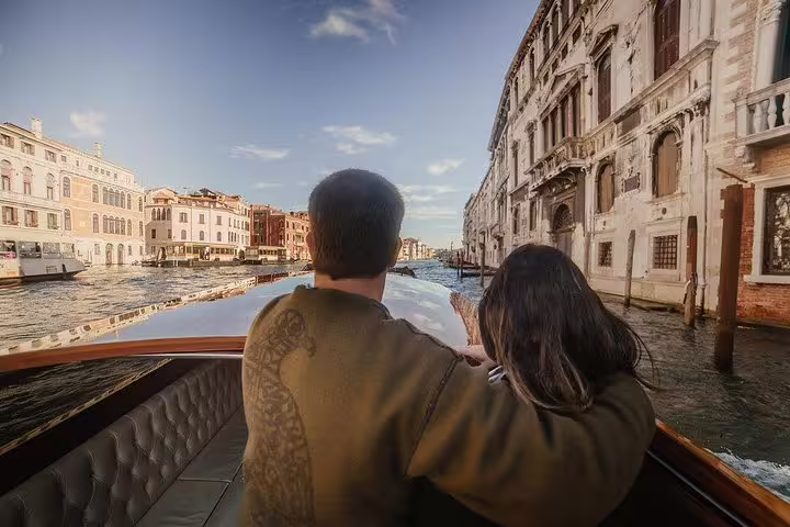 Couple enjoying a private boat tour on the Grand Canal, exploring Murano and Burano with stunning Venetian views.