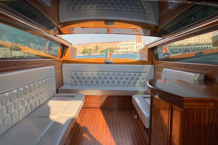 Luxurious interior of a wooden boat cruising the Grand Canal on a shared tour from San Marco Square.