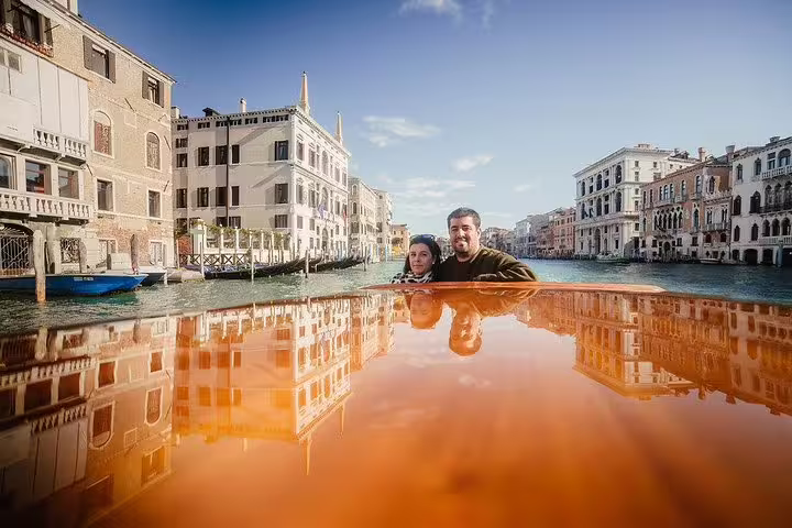 Couple enjoying a private boat tour on the Grand Canal with historic Venetian architecture in the background.