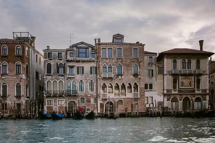 Elegant Venetian buildings line the Grand Canal, showcasing unique architecture on a cloudy day.