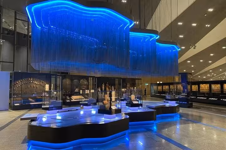 Grand Egyptian Museum gallery with blue-lit displays and artifacts, visited on Hurghada to Pyramids day trip