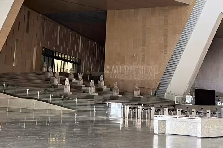 Grand Egyptian Museum main hall and steps in Cairo, private guided tour view with seated statues and signage