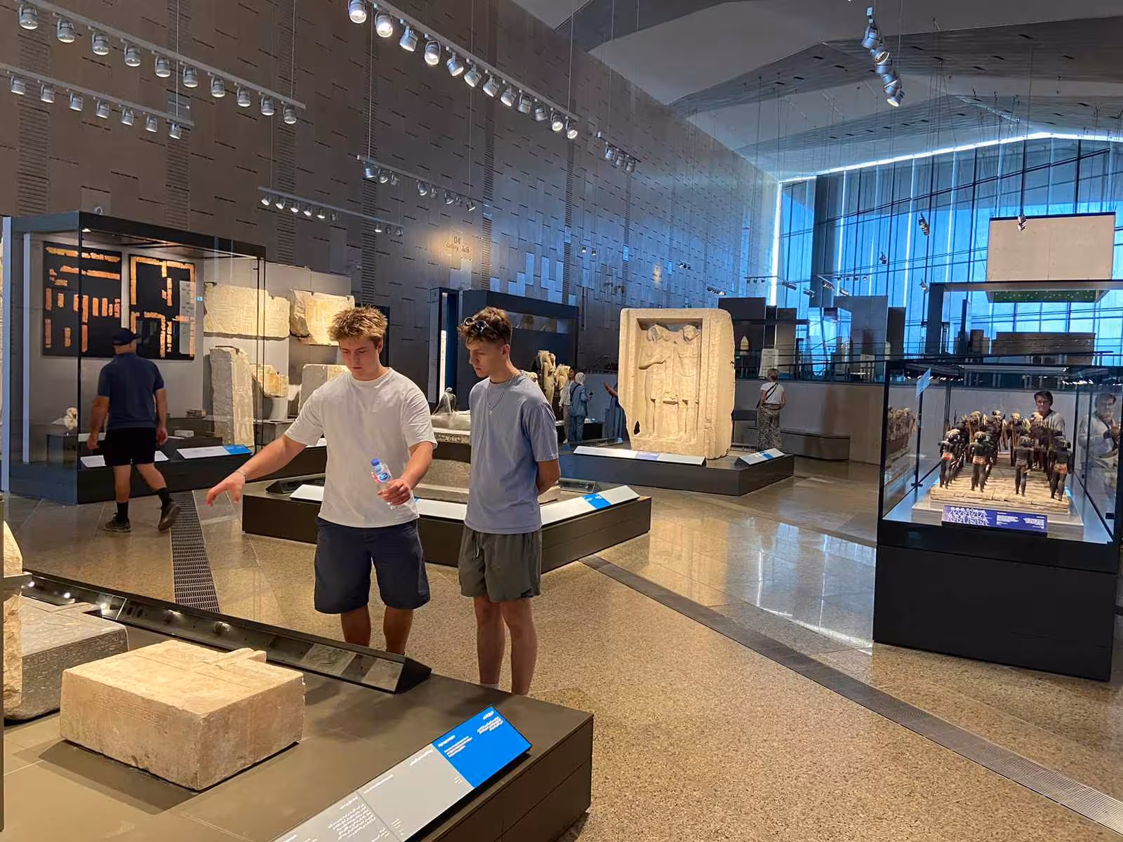 Guests exploring Grand Egyptian Museum Cairo exhibits, stone reliefs and statues on a guided museum tour