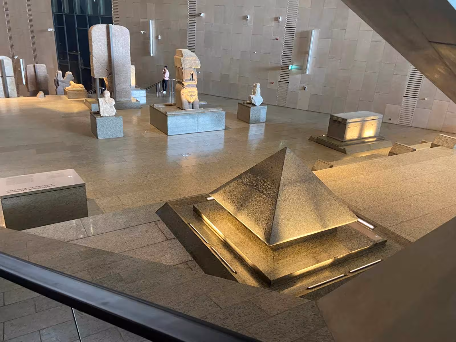 Grand Egyptian Museum interior gallery with pyramid-shaped sculpture and monumental statues, Giza Cairo tour