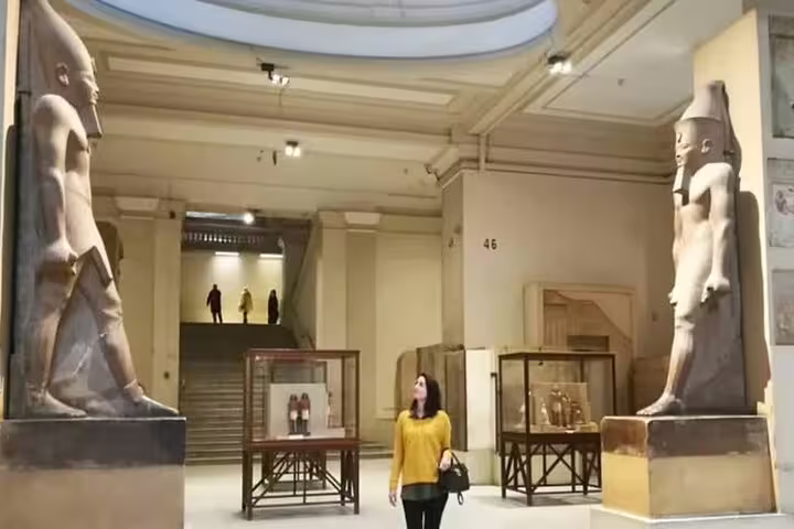 Interior gallery at Grand Egyptian Museum GEM with two ancient statues and display cases on a 3-hour Cairo tour