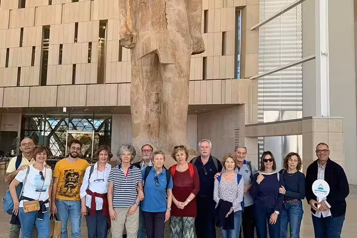 Tour group posing beneath a colossal statue inside the Grand Egyptian Museum on a 3-hour GEM guided tour