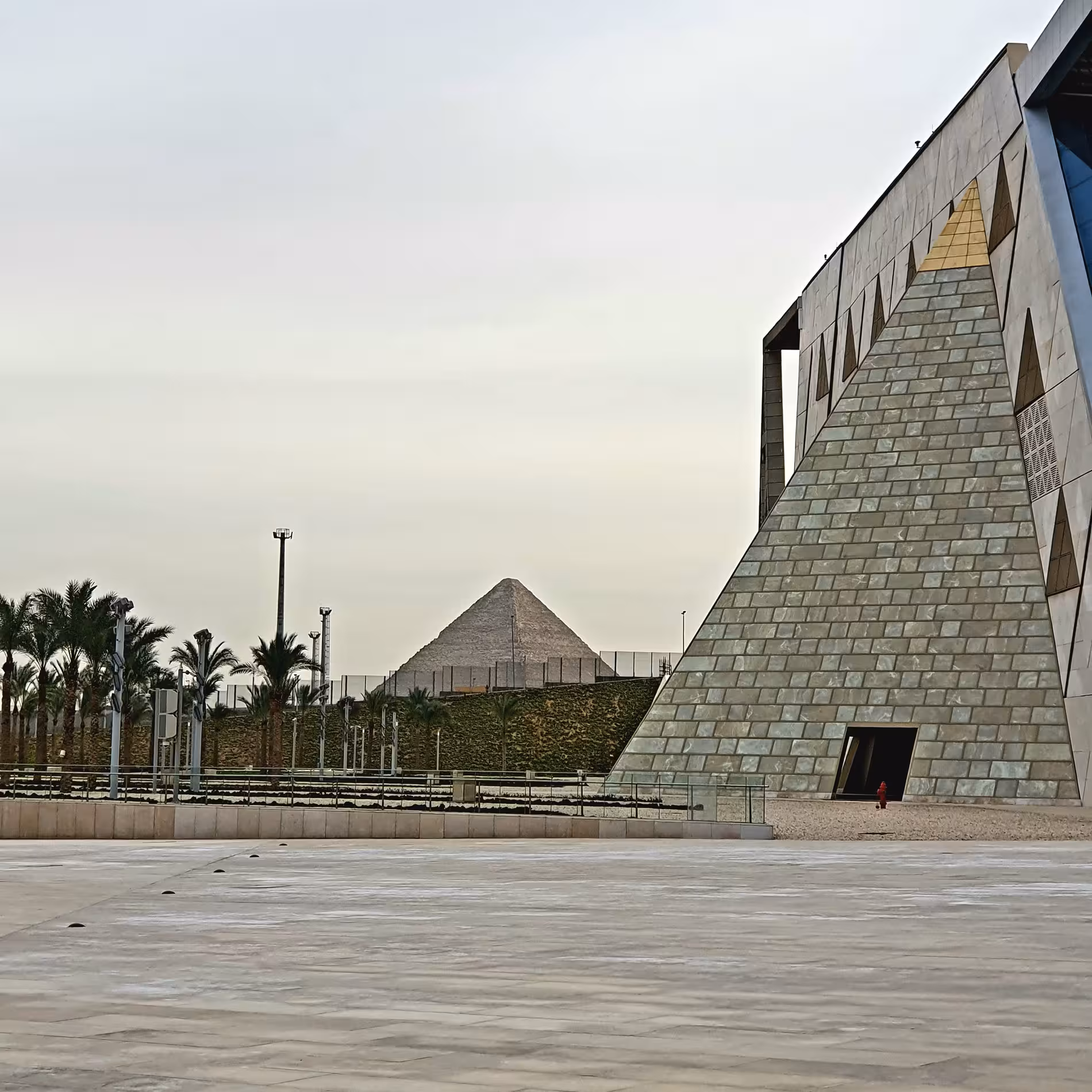 Grand Egyptian Museum pyramid facade with ancient Giza pyramid visible in background