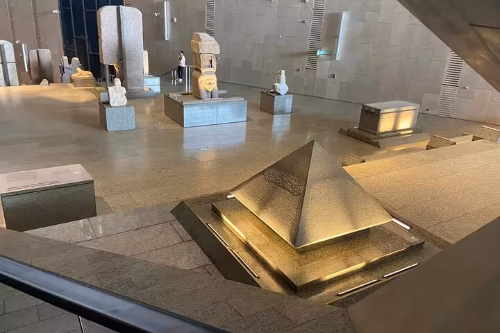 Grand Egyptian Museum interior with pyramid-inspired sculpture and ancient artifacts on a Cairo day tour to Giza Pyramids