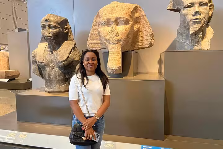 Visitor posing with colossal pharaoh heads at the Grand Egyptian Museum, Cairo, on Giza Pyramids tour