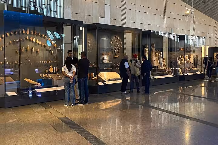Visitors viewing ancient Egyptian artifacts inside the Grand Egyptian Museum on a Giza Pyramids day tour