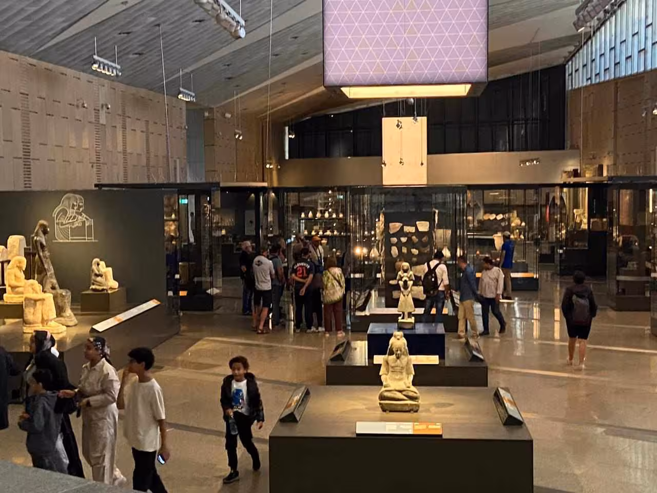 Grand Egyptian Museum main hall with visitors and artifacts, part of full-day Giza Pyramids and lunch tour