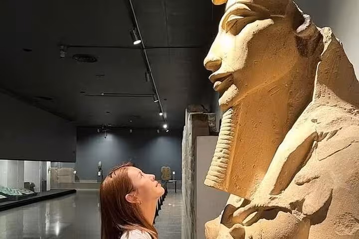 Visitor admiring ancient pharaoh statue inside Grand Egyptian Museum Cairo on half-day tour with tickets