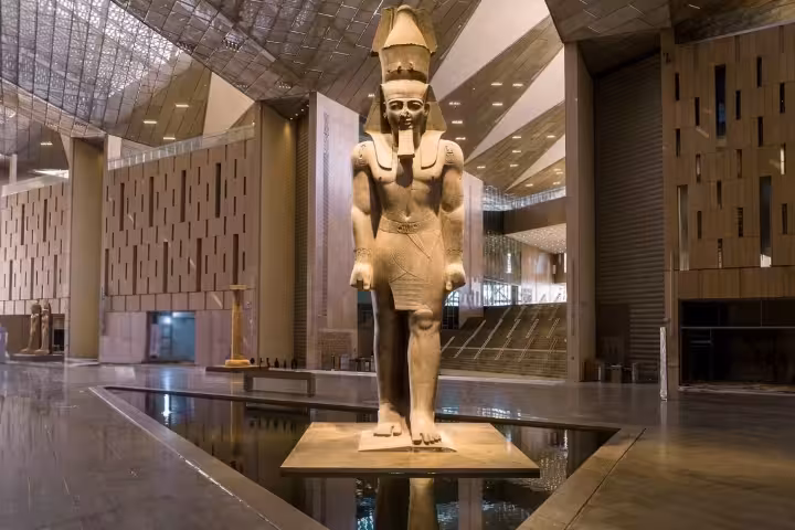 Ancient Egyptian pharaoh statue inside the Grand Egyptian Museum modern interior hall