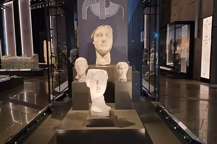 Grand Egyptian Museum gallery with ancient Egyptian statue heads on display, highlight of Giza day tour