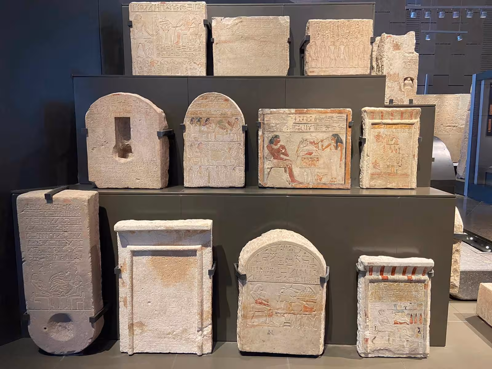 Ancient Egyptian stelae and painted limestone reliefs on display at the Grand Egyptian Museum in Giza