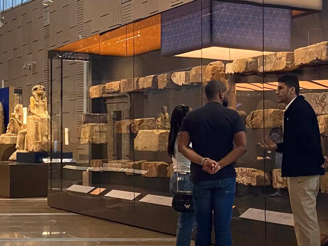 Visitors viewing carved stone temple blocks at the Grand Egyptian Museum, Cairo, on a guided museum tour