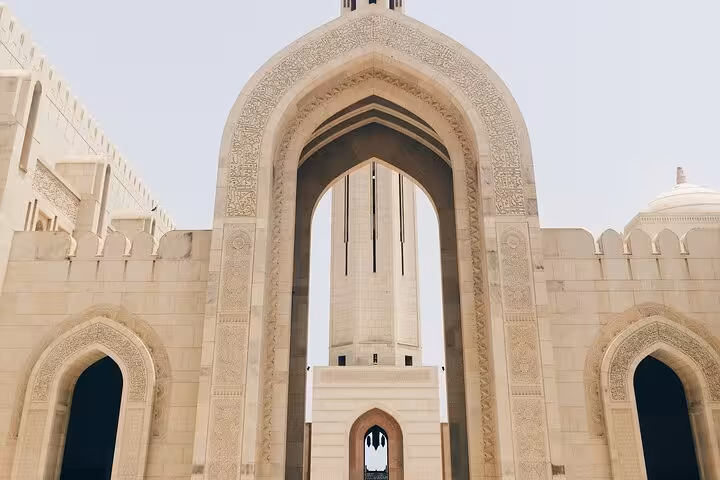 Grand Mosque ornate archway with intricate Islamic carvings and minaret view on Muscat city tour Oman