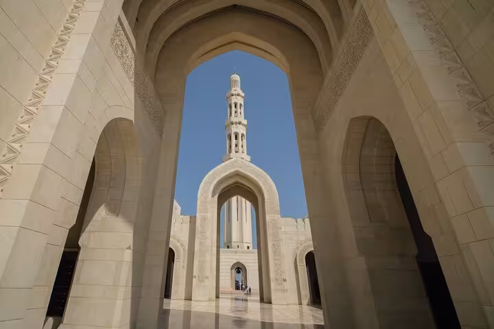 Grand Mosque minaret framed by ornate white stone arches on a private Muscat city tour in Oman