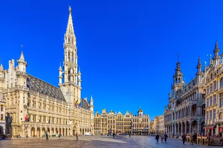 Grand Place Brussels with ornate Gothic Town Hall tower and gilded guild houses under blue sky