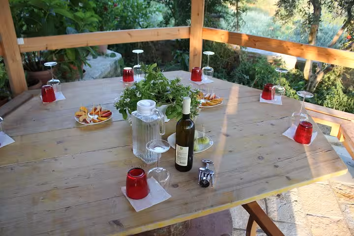 A rustic table set with wine, glasses, and snacks for the Grand Wine Tasting & Food Tour in Berat's scenic vineyard.