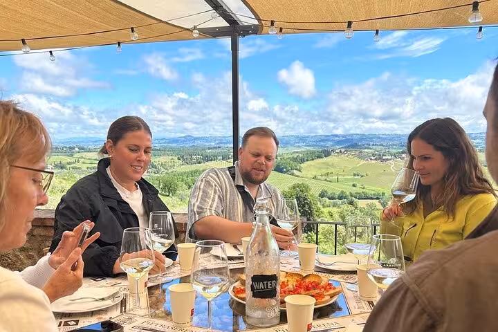 Tourists savoring wine and Italian cuisine with scenic views of Tuscany's rolling vineyards.