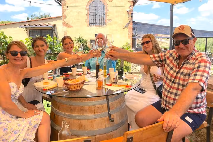 Group enjoying a wine tasting at a Tuscan winery, seated around a table of local delicacies.