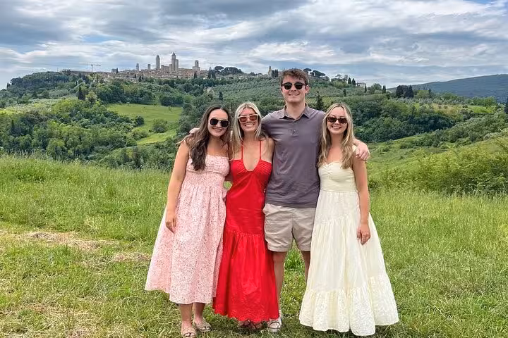 Tourists posing with the picturesque skyline of San Gimignano in the background during a Tuscany tour.