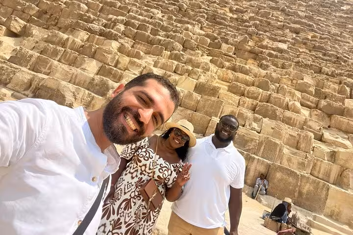 Group selfie with guide at the base of the Great Pyramid of Giza during a private Cairo pyramids and Sphinx tour