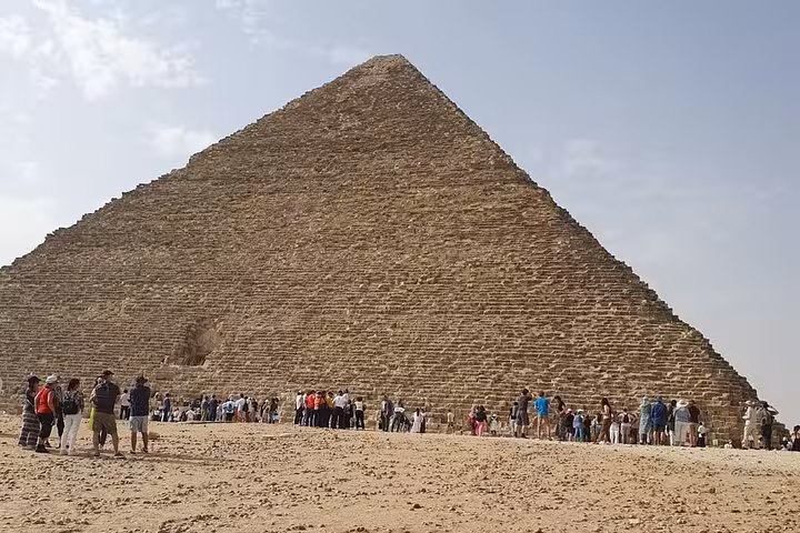 Tourists gathered at the base of the Great Pyramid of Giza, Cairo, on a guided pyramids and museum tour