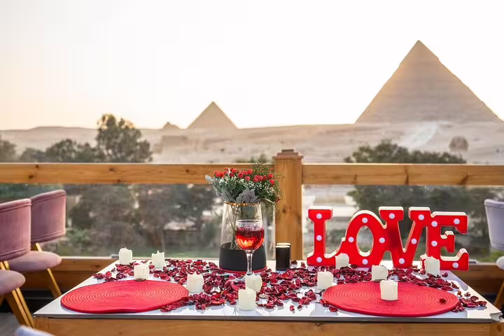 Romantic lunch table on Great Pyramid Inn terrace with rose petals and Giza Pyramids view in Cairo