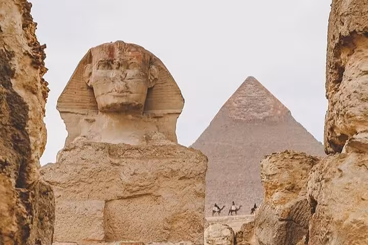 Close-up of the Great Sphinx framed by rocks with Giza pyramid, private Hurghada to Cairo pyramids tour