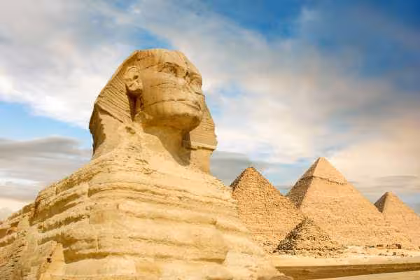 Great Sphinx with Giza Pyramids under blue sky, key stop on the 13-day Ultimate Egyptian Odyssey Egypt tour