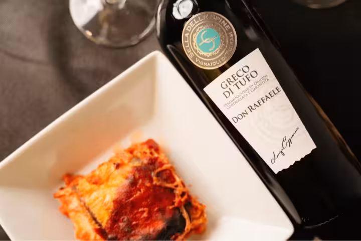Greco di Tufo wine bottle beside baked pasta, part of Taurasi full tasting with local food pairings