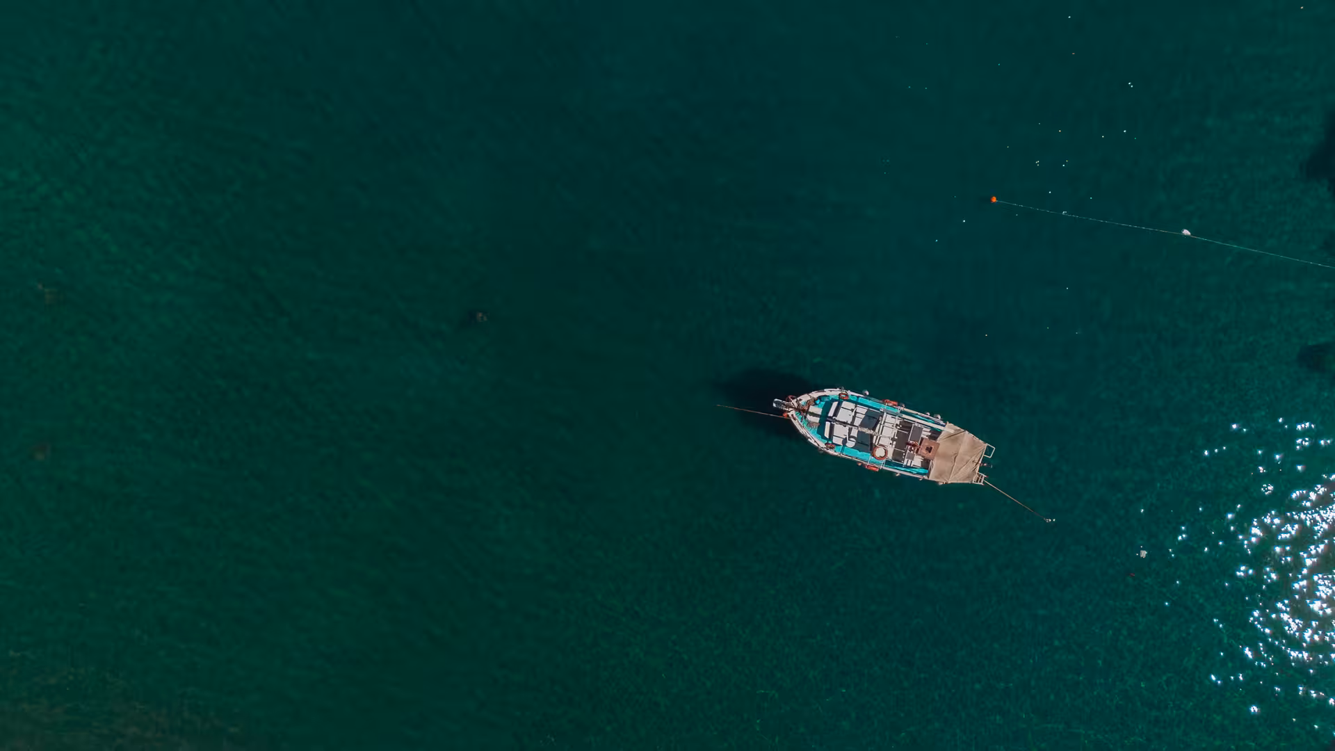 Traditional Greek boat anchored in crystal-clear Aegean waters off Ikaria, ideal for coastal cruising and village hopping tours