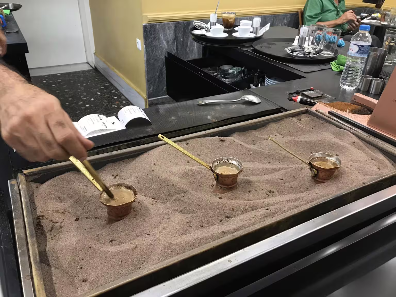 Greek coffee brewed in hot sand with copper briki, authentic tasting on a gourmet food walking tour Athens