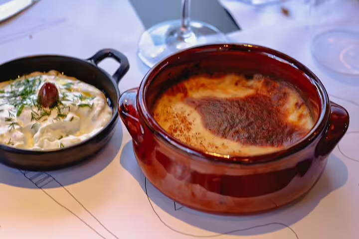 Greek cooking class Athens dishes served, creamy tzatziki and baked casserole for rooftop dinner with Acropolis view
