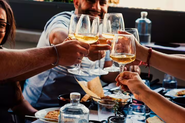 Guests clink wine glasses at rooftop dinner after Greek cooking class in Athens, Acropolis view experience